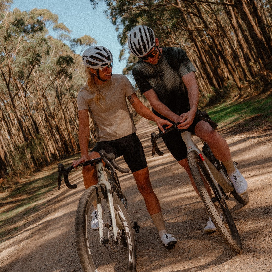 Two riders on a forest gravel road in the Enduro Tee and the Enduro Mesh Tee